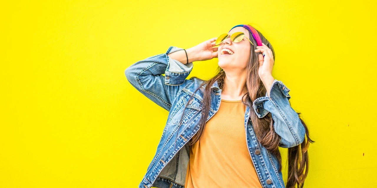 smiling-woman-looking-upright-standing-against-yellow-wall-1536619